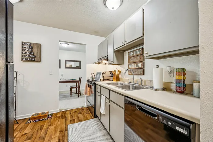Charming kitchen with warm wooden flooring, sleek countertops, and cozy dining nook, enhanced by inspirational decor for a homely feel.