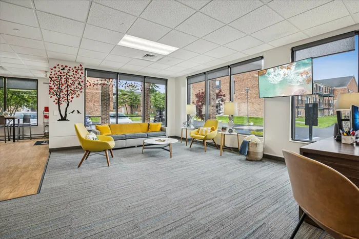 Inviting modern living area with large windows, vibrant decor, and comfortable seating, perfect for relaxation and enjoying natural light.