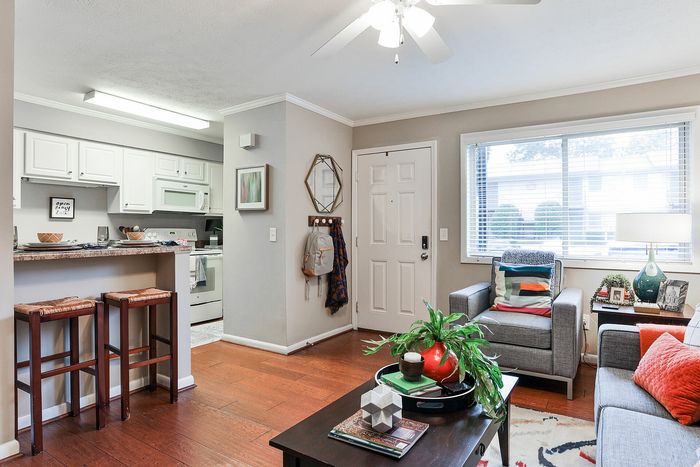 Cozy and bright living room with elegant hardwood floors, modern kitchen with breakfast bar, and stylish decor for a welcoming atmosphere.