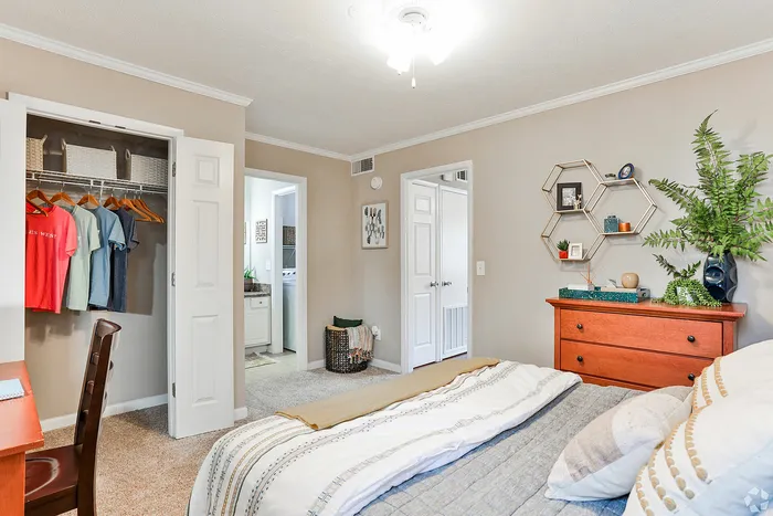 Bright and welcoming bedroom with elegant decor, featuring a large closet, cozy bedding, and a stylish dresser with decorative accents.