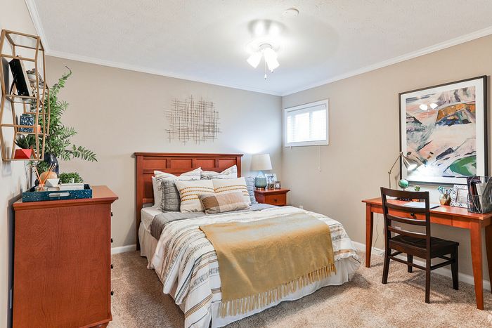 Cozy and inviting bedroom featuring elegant wooden furniture, plush bedding, and a stylish desk area with artistic accents.