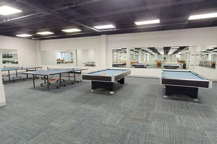 Spacious recreation room featuring stylish billiard and ping pong tables surrounded by modern mirrors, ideal for leisure and entertainment.