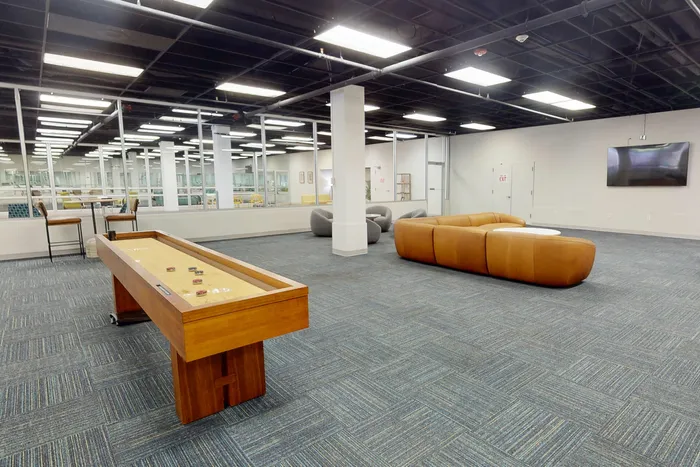 Modern recreation area with shuffleboard table, plush seating, and sleek design perfect for social gatherings.