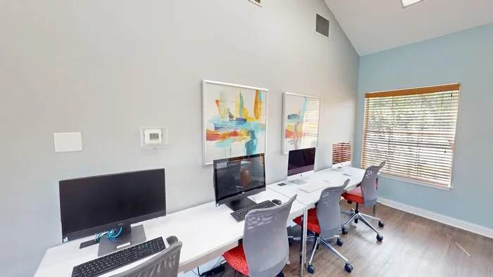 Sleek and modern workspace with four computer stations, colorful abstract art, and bright natural light through large windows.