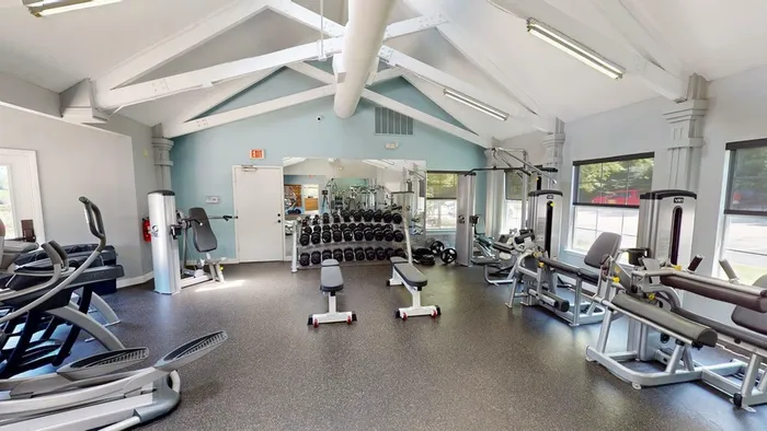 Bright and fully equipped fitness center with modern gym equipment, featuring cardio machines and free weights in a spacious setting.