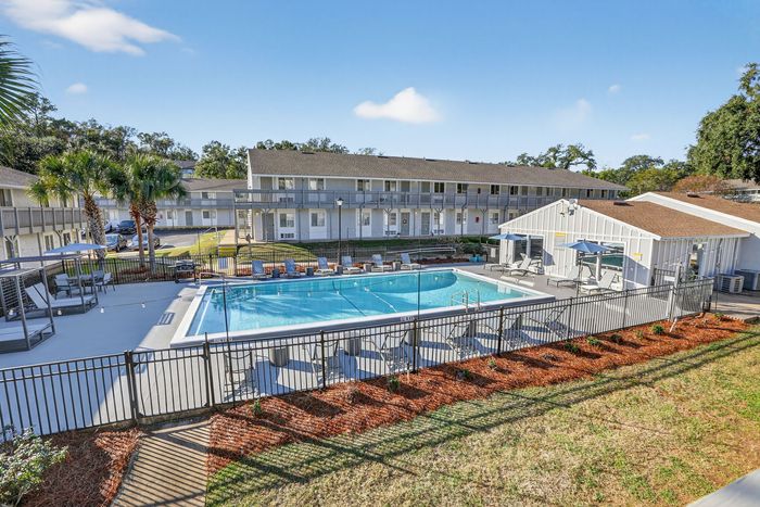 Inviting apartment complex with a sparkling pool, surrounded by relaxing lounge chairs and lush landscaping, showcasing a perfect blend of comfort and community living.
