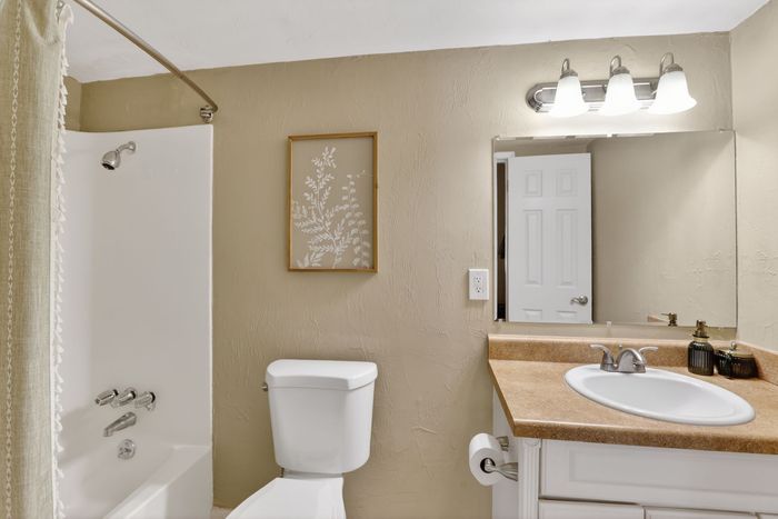Elegant bathroom featuring a chic vanity with a modern sink, tasteful wall art, and a well-lit mirror for a luxurious touch.