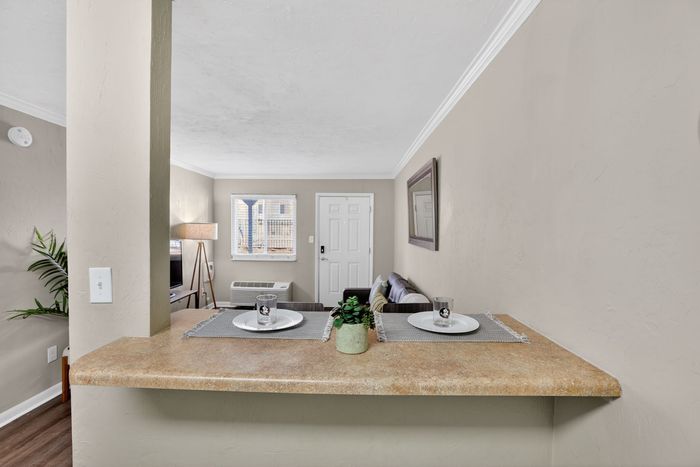 Charming living space with a cozy seating area, stylish bar countertop, and large window offering natural light.