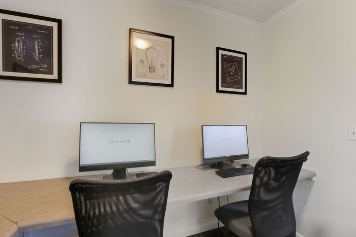 Modern co-working space featuring elegant framed artwork, dual computer stations, and ergonomic seating for a sleek work environment.