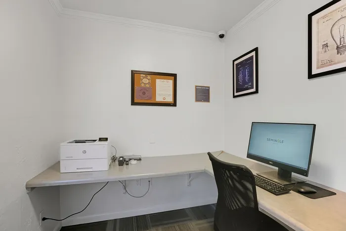 Modern home office corner with sleek desk setup featuring a large monitor, comfortable chair, and stylish wall art.