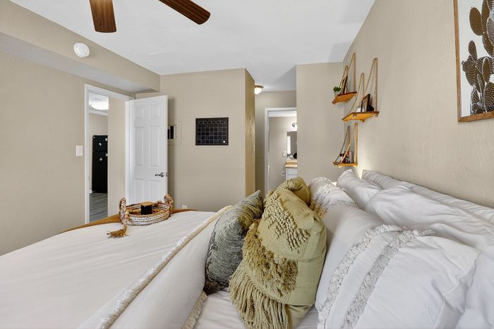 Inviting bedroom showcasing elegant decor and cozy pillows, featuring warm lighting and stylish shelving for a relaxing ambiance.