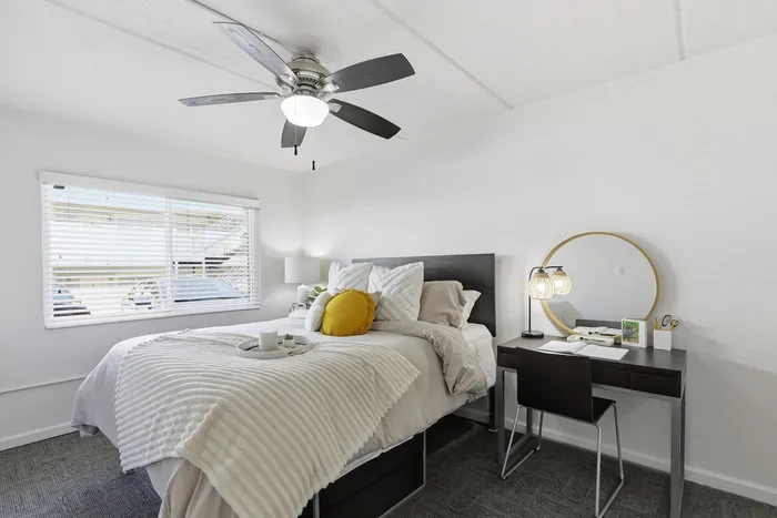 Modern bedroom with a plush bed, stylish desk, and a large window offering natural light.