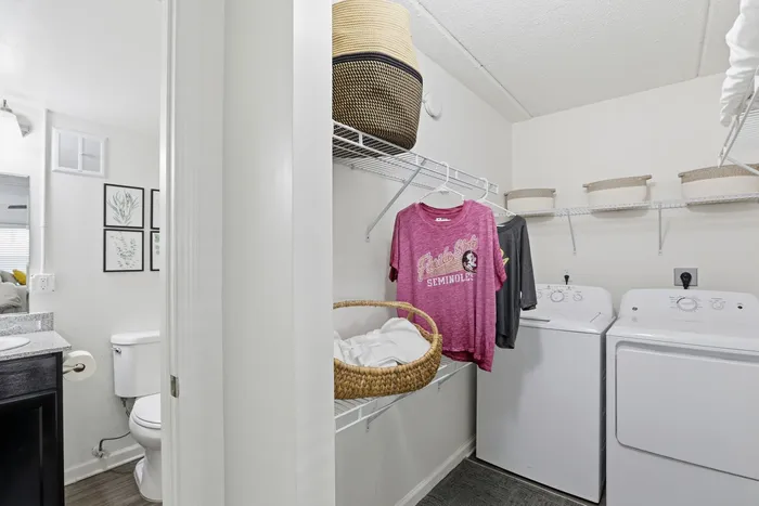 Modern laundry room with stylish wire shelving, washer and dryer set, and convenient adjacent bathroom access.