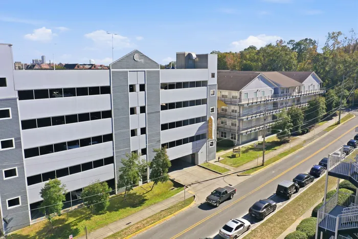 Bright and modern residential building with ample parking and lush surroundings on a sunny day.