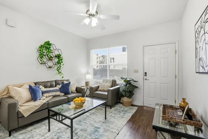 Inviting living room with chic gray sofas, vibrant blue pillows, and refreshing greenery on a modern wall shelf.