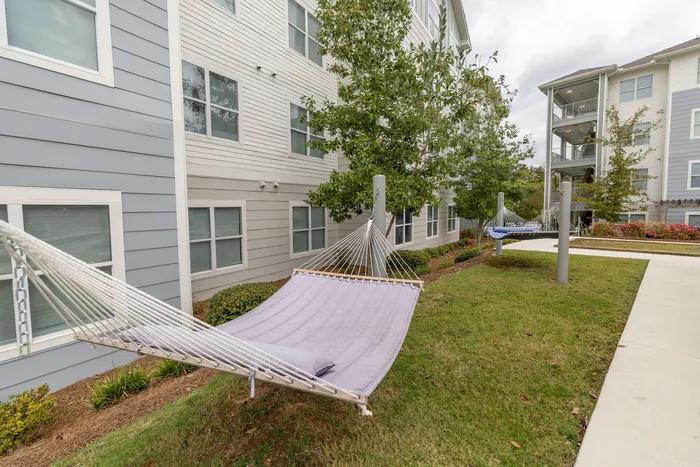 Inviting outdoor area with comfortable hammocks and lush greenery, perfect for relaxation at a modern apartment complex.