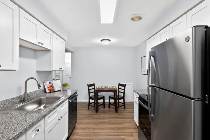 Modern kitchen with granite countertops, stainless steel appliances, and cozy dining area for two.