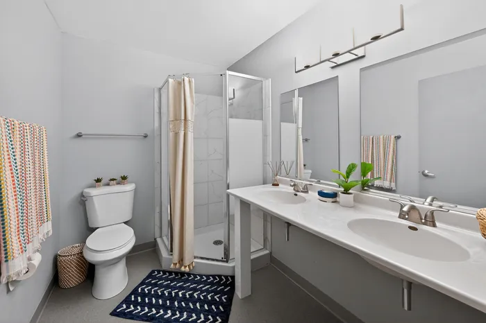 Elegant bathroom with a modern design featuring a sleek double vanity, cozy shower, and stylish decor accents.