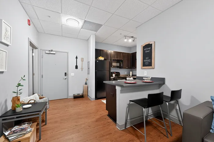 Inviting kitchen and entrance area with modern dark wood cabinets and a stylish breakfast bar, featuring cozy seating and vibrant decor.