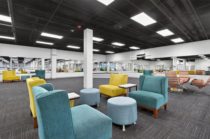 Modern lounge area with vibrant seating and mirrored walls in a spacious community room, perfect for social gatherings.