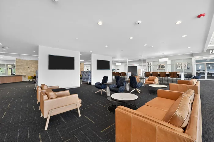 Modern and spacious lounge area featuring chic leather seating, contemporary decor, and ample natural lighting, perfect for relaxation and social gatherings.