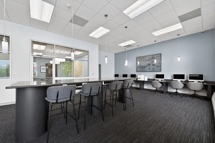 Modern apartment lounge with sleek workstations, high ceilings, and contemporary lighting, perfect for remote work and meetings.