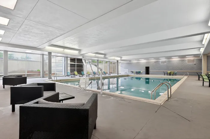 Modern indoor pool area with sleek lounge seating and expansive glass windows, perfect for relaxation and recreation.