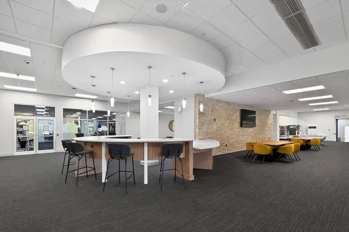 Elegant communal area with modern bar seating, stylish pendant lighting, and a cozy dining space featuring plush mustard chairs.