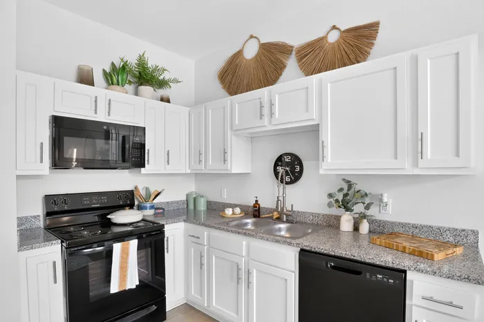Elegant kitchen with sleek white cabinets, modern black appliances, and tasteful decor creating a warm, inviting atmosphere.