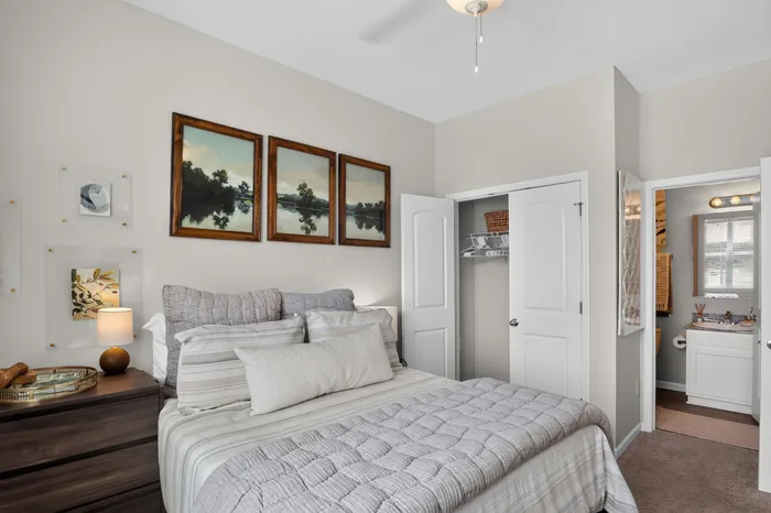 Charming bedroom with cozy bedding, elegant art prints, and a glimpse into a modern bathroom.