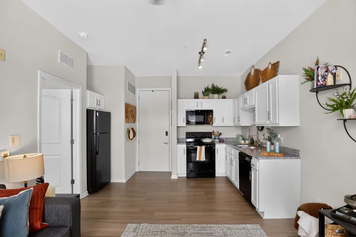 Modern open kitchen with elegant white cabinets, sleek black appliances, and stylish decor, featuring a cozy seating area for a welcoming atmosphere.