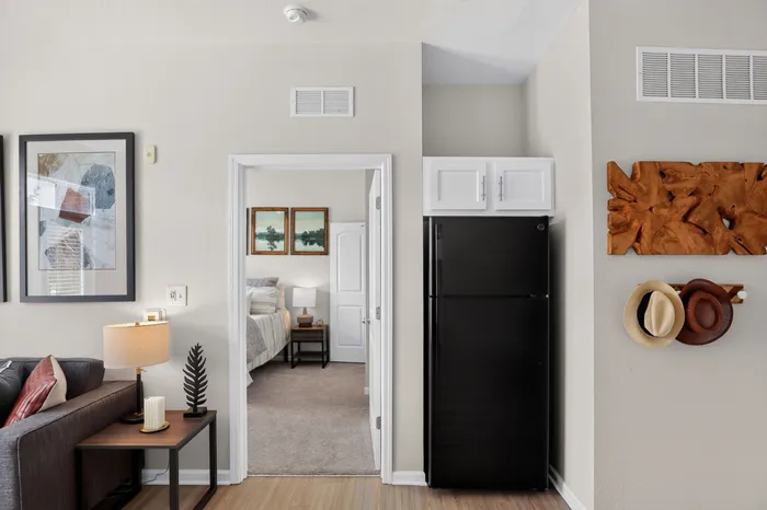 Modern apartment interior with a cozy living area leading into a stylish bedroom, featuring elegant wall art and contemporary decor.