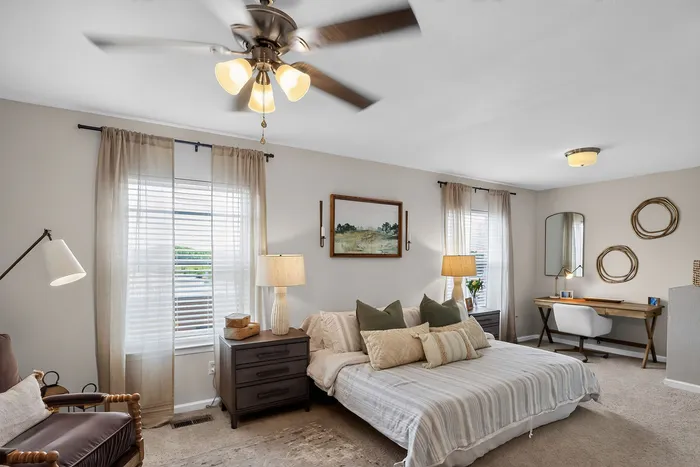 Inviting bedroom with warm lighting, chic decor, and a cozy workspace exuding comfort and style.