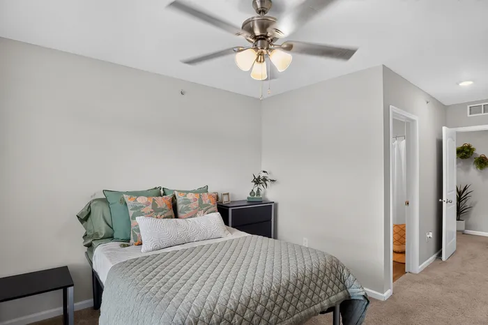 Cozy bedroom featuring elegant décor, plush bedding, and modern ceiling fan, with en-suite bathroom access.