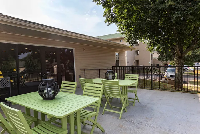 Outdoor patio with dining tables &ndash; Open-air patio with light green dining tables and chairs, ideal for social gatherings or relaxing outside at The Field Apartments.