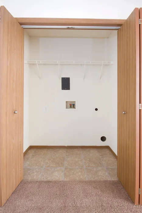 Closet-style laundry area with washer and dryer connections, upper shelf for storage, and louvered doors that close for a clean look.