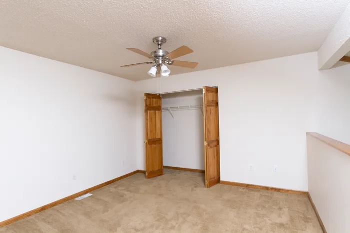 Cozy bedroom layout featuring an open closet with double doors and overhead fan, ideal for comfortable living