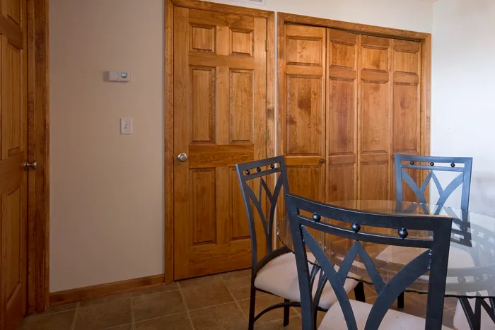 Dining area featuring metal-frame chairs with padded seats, tile flooring, and a wall of natural wood closet doors offering additional storage.
