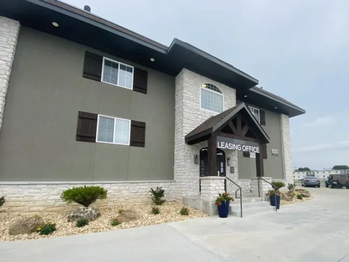 Two-story building with gray and stone facade, dark trim, and entrance sign reading