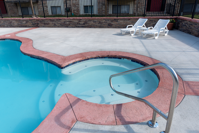 Close-up of small wading pool connected to the main pool at Seminole Apartments with curved seating and metal handrail.
