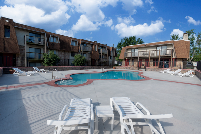 Lounge chairs arranged poolside at Seminole Apartments, with clear blue skies above and surrounding buildings visible.