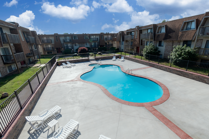 Large outdoor pool at Seminole Apartments in Springfield, MO, surrounded by lounge chairs and well-maintained landscaping.