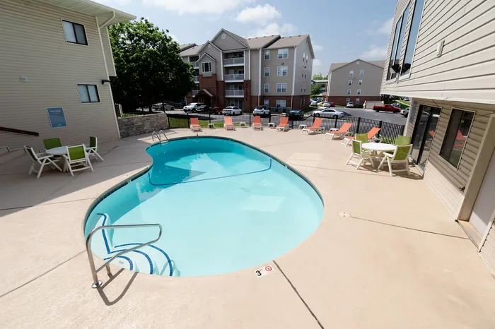 Poolside view facing apartment buildings &ndash; Resort-style pool with seating areas, trees for shade, and views of the surrounding multi-level residential buildings at The Field Apartments.