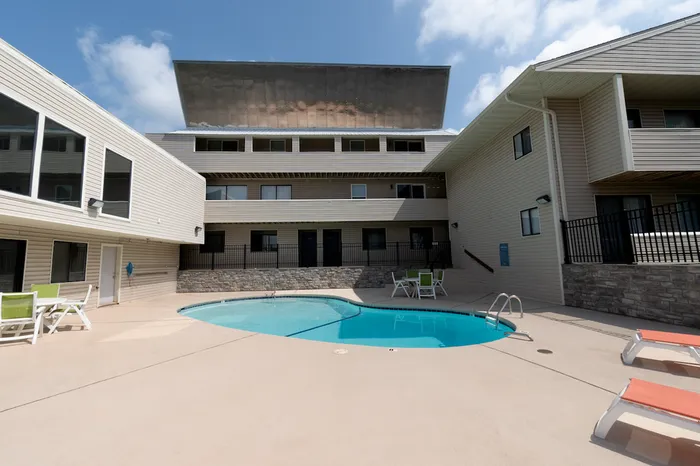 Outdoor pool courtyard &ndash; Private outdoor pool area surrounded by a multi-story apartment building with seating and lounge chairs at The Field Apartments.