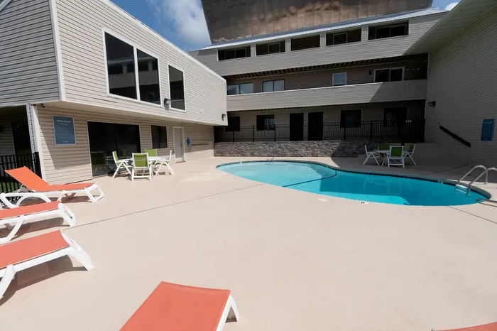 Pool courtyard with seating &ndash; Bright pool area with patio furniture and ample space to relax, framed by the apartment community&rsquo;s exterior design at The Field Apartments.