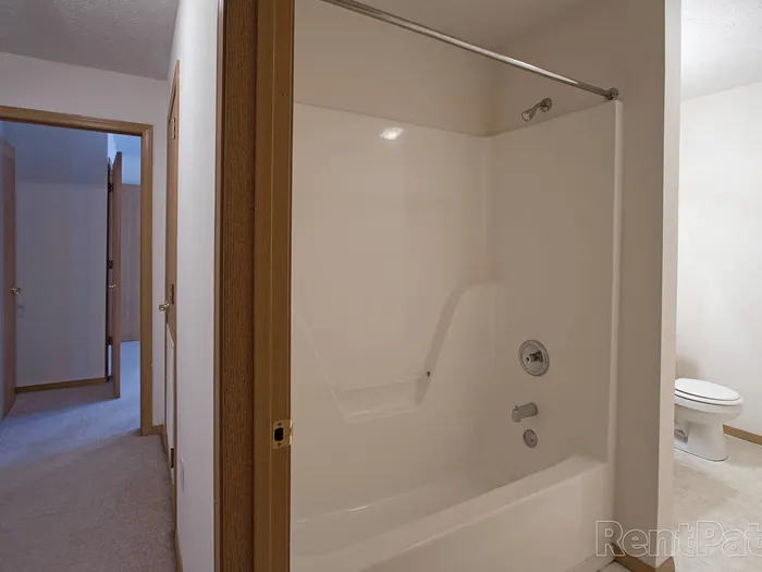 Clean, modern bathroom at Huntley Ridge Apartments featuring a white fiberglass tub and shower combo with chrome fixtures and a curved shower rod.