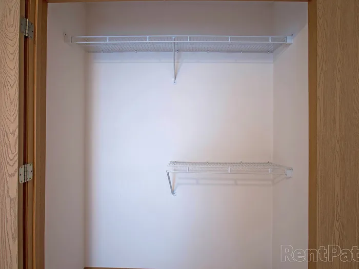 Interior view of a closet equipped with wire shelves and hanging space, providing practical storage solutions in Huntley Ridge apartments.