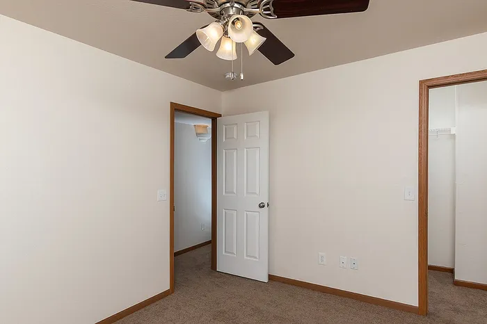 Spacious bedroom with neutral finishes, shown from the corner view highlighting closet and hallway door access.