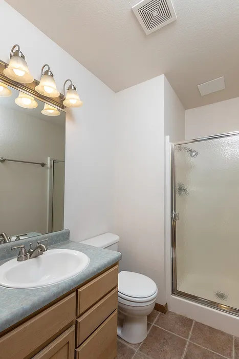 Second bathroom featuring a full-size shower and tub combo with sliding glass doors, single vanity with under-sink storage, and large wall mirror.