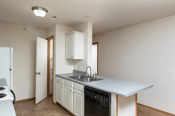 Updated kitchen featuring white cabinetry, a breakfast bar, and double stainless steel sink, perfect for everyday living in this Springfield, MO apartment.